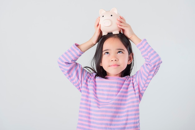 Little Asian girl saving money in a piggy bank