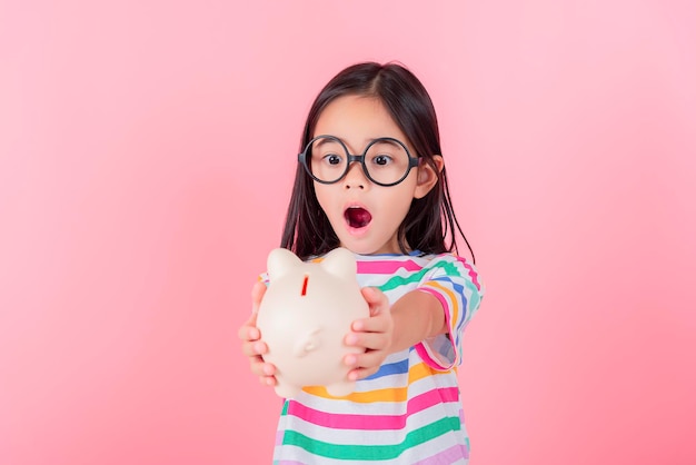 Little Asian girl saving money in a piggy bank