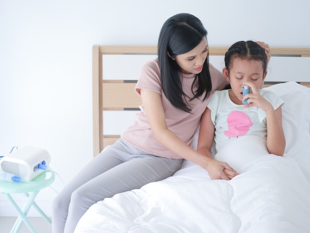 Little Asian girl sick laying  on bed in hospital room and her mom was take care beside.