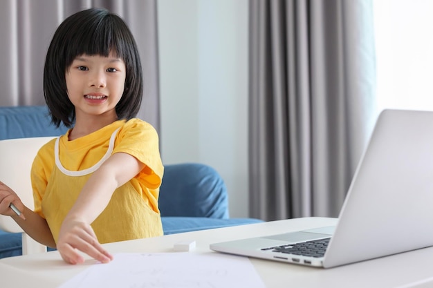 Little asian girl student study online using laptop computer at home