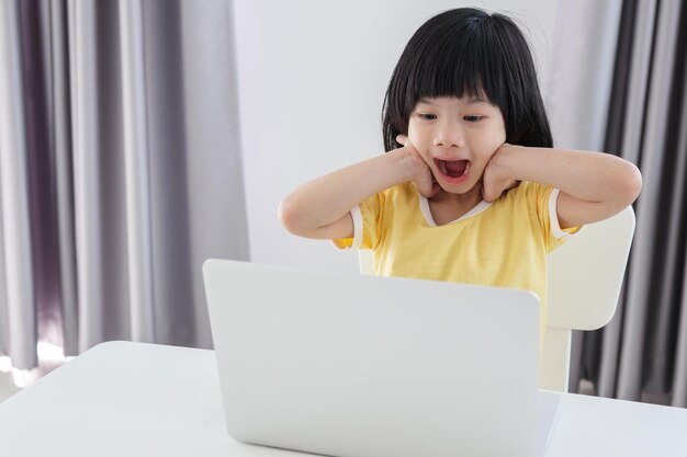집에서 노트북 컴퓨터를 사용하여 온라인으로 공부하는 어린 아시아 여학생