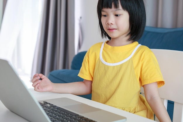 집에서 노트북 컴퓨터를 사용하여 온라인으로 공부하는 어린 아시아 여학생