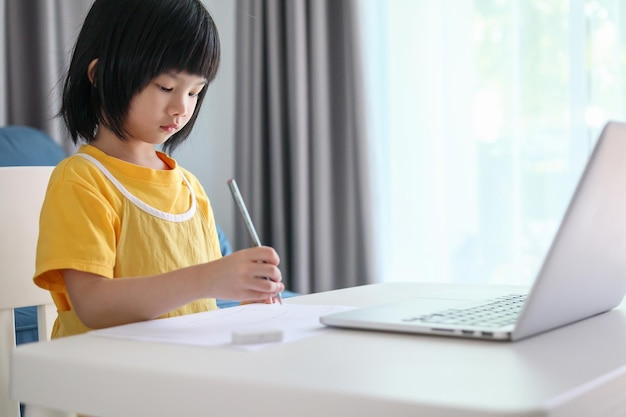 Little asian girl student study online using laptop computer at home