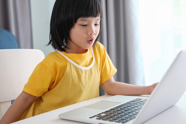 Little asian girl student study online using laptop computer at home