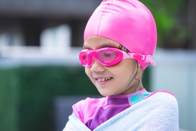 Little asian girl swimming with glasses and towel