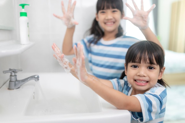 Little Asian girls wash their hands in the bathroom. Soft focus. Copy space.