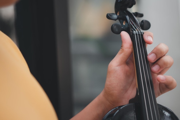 Un ragazzino asiatico che suona e pratica lo strumento a corda musicale del violino contro il concetto di casa