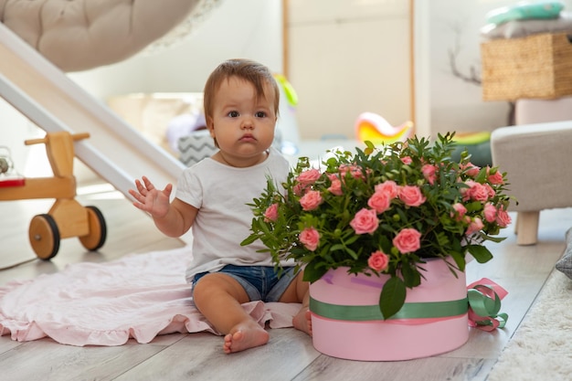 Little babe girl with gift box of roses at home
