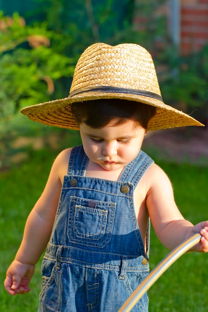 little baby boy gardener watering the grass in serious fashion