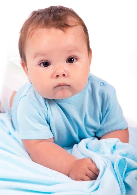 白い背景の上のベッドに横たわって小さな男の子