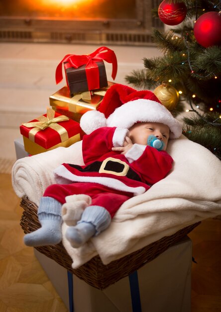 Little baby boy in Santa costume sleeping on Christmas night at living room