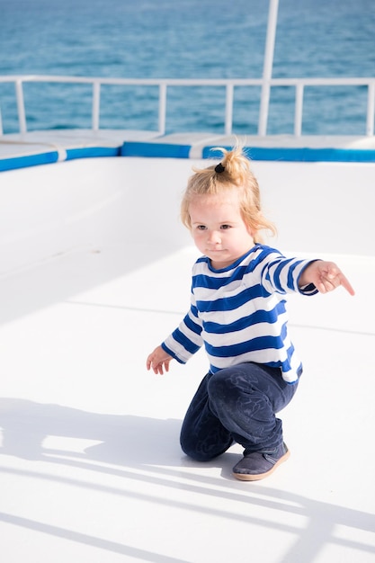 Little baby captain on boat on summer cruise nautical fashion