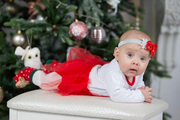 Little baby at Christmas. Three-month-old girl against the background of the Christmas tree decoration.