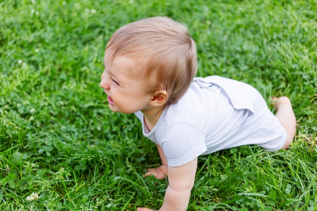 잔디에 크롤 링하는 작은 아기. 아이가 웃어요. 아이를위한 야외 활동.