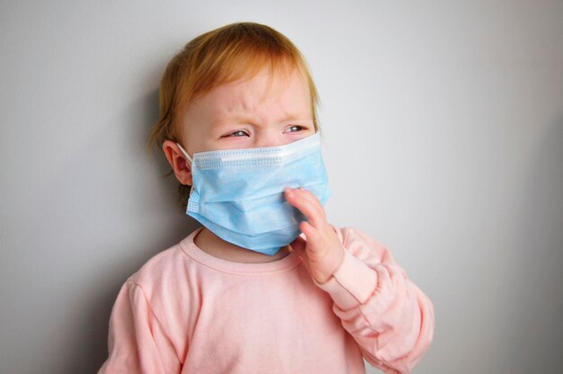 Photo little baby crying in a medical mask