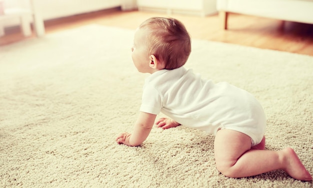 Photo little baby in diaper crawling on floor at home