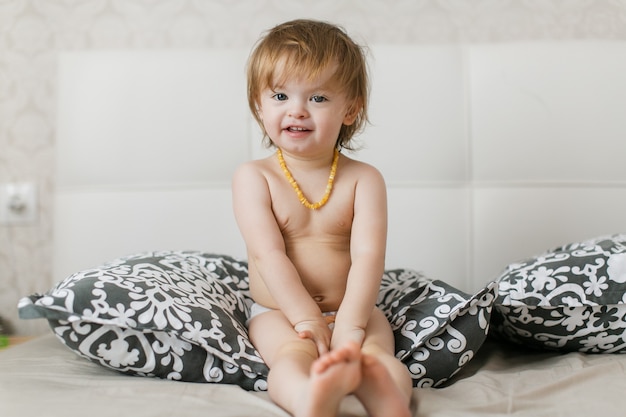 little baby in a diaper lies on the bed and laughs