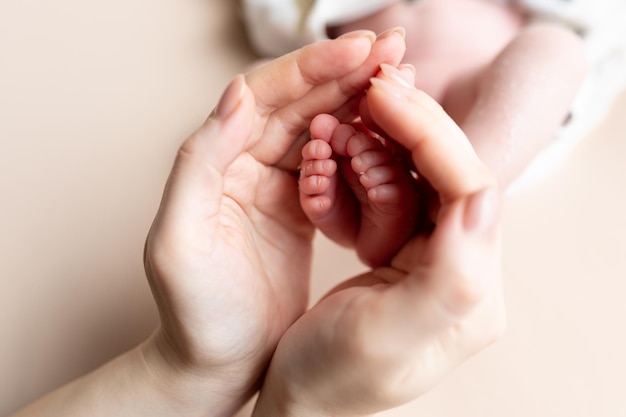 ママの手の中の小さな赤ちゃんの足。新生児。つま先