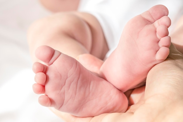 Piccoli piedi del bambino nella mano delle madri concetto di maternità e cura del bambino