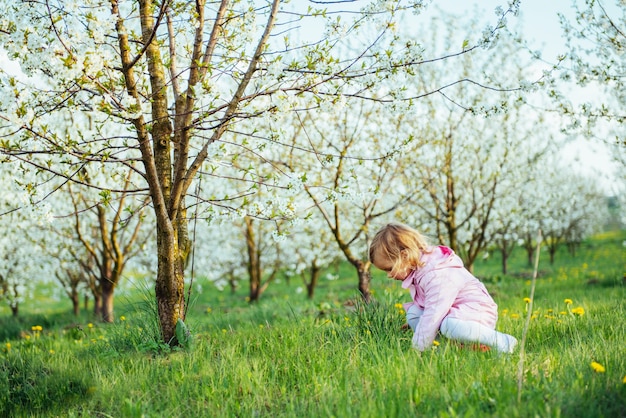 開花樹の間を走る3歳の女の赤ちゃん