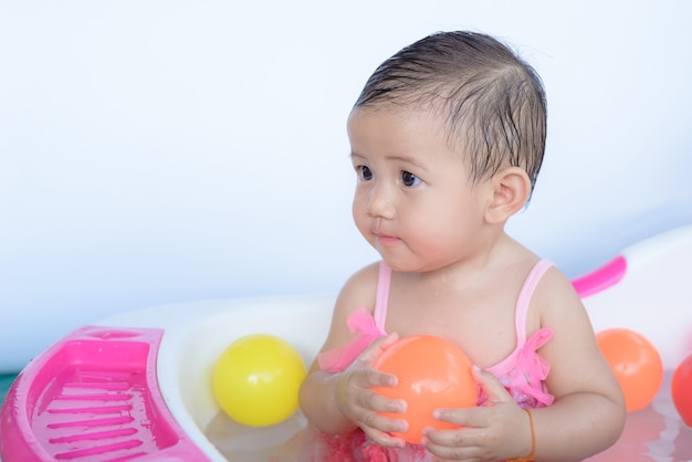 little baby girl in the bath playing  ball.