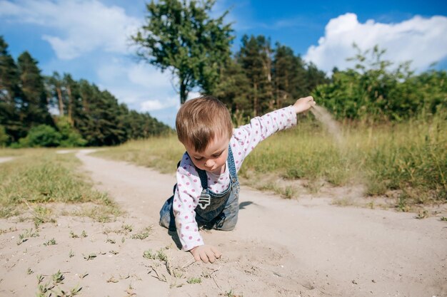 Little baby girl in denim clothes playing in the sand