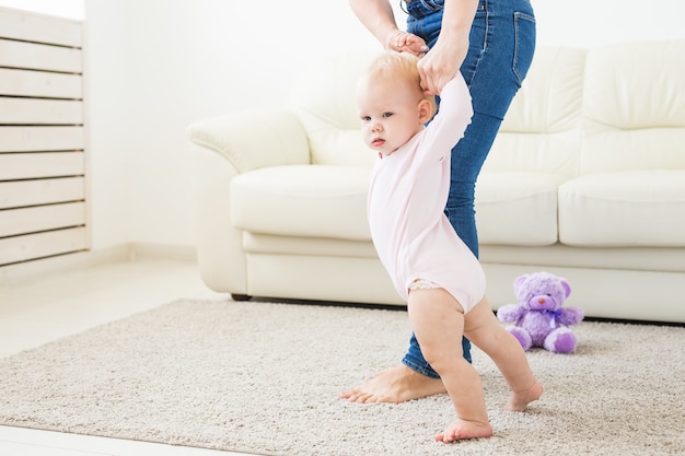 Little baby girl first steps with the help of mom