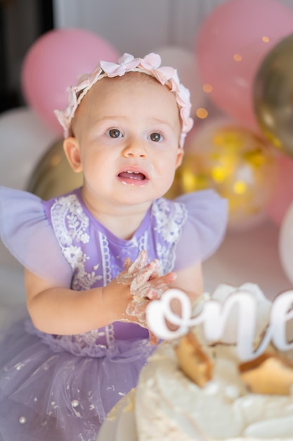 little baby girl on the floor and playing with his cake on his first birthday Smash cake