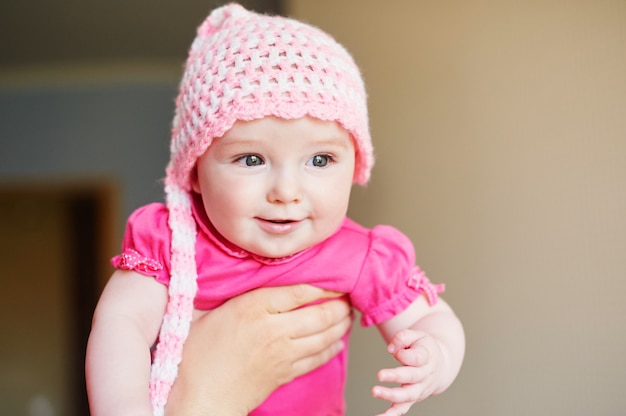 Little baby girl in a knitted hat on hands at mum