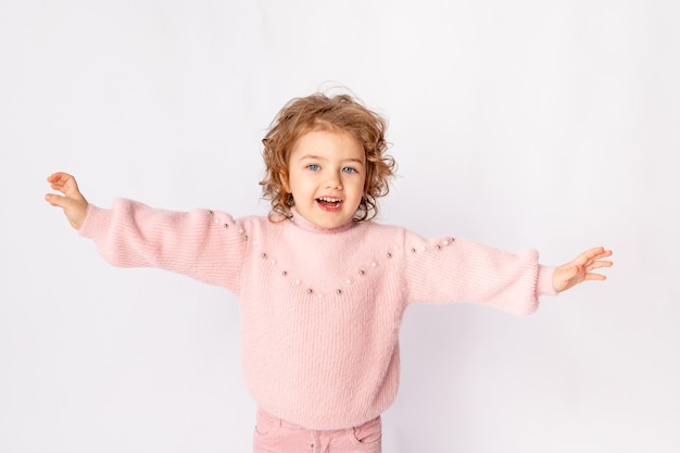 Маленькая девочка в розовой зимней одежде на белом фоне радуется, место для текста