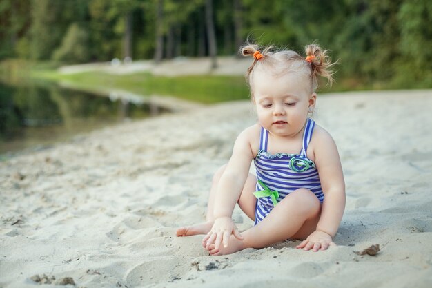 Little baby girl playing in the sand.