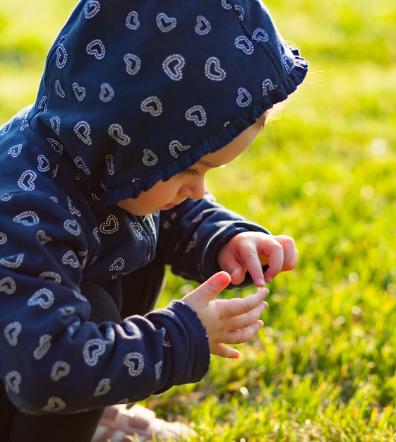 Маленькая девочка играет и собирает ромашки.