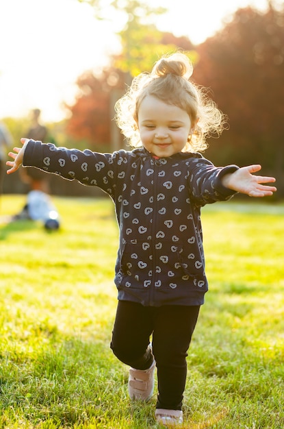 Little baby girl plays in the park in backlight.