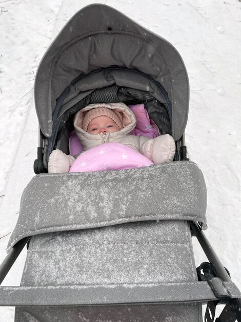 雪が積もった冬の日にベビーカーに乗った小さな女の子