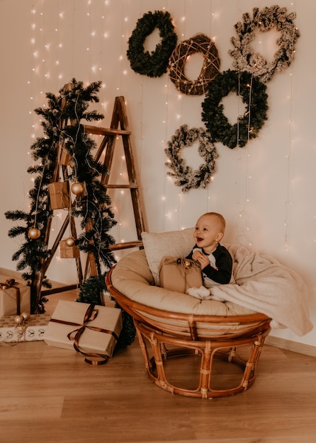 Piccola neonata che si siede nella sedia e che gioca. mattina di natale. interni di capodanno. celebrazione di san valentino