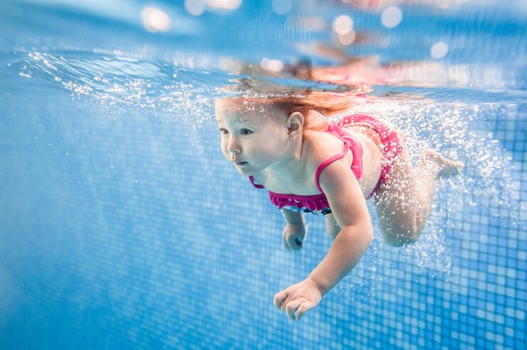 Photo little baby, girl swimming under water in paddling pool. diving baby. learning infant child to swim. enjoy of swimming and bubbles.