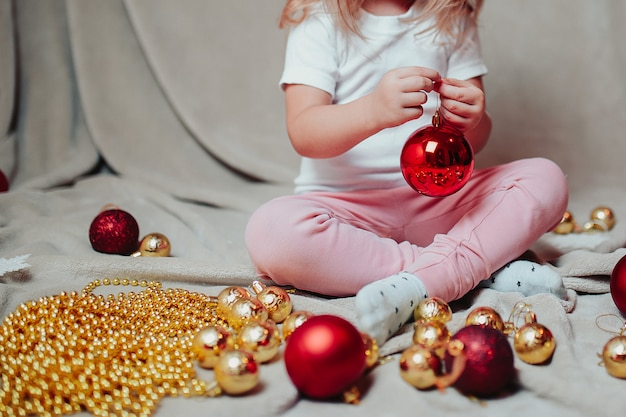 Little baby girl with christmas ornaments around. 