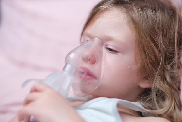 Little baby girl with oxygen mask lying on hospital bed or at home