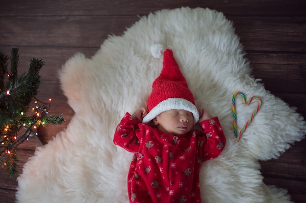 写真 サンタクロースの赤い帽子をかぶった小さな赤ちゃんがクリスマスを祝う