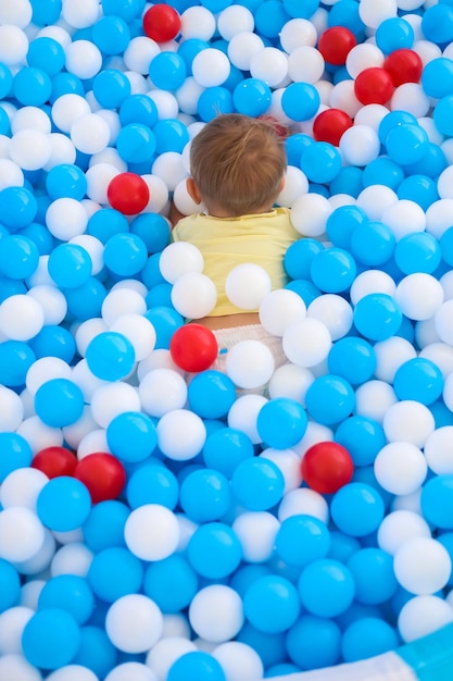 Foto un piccolo bambino che gioca nella piscina per bambini piena di palline di plastica