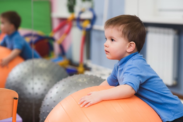 Little baby plays with a fitball in the gym