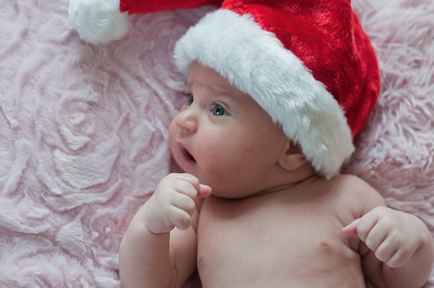 Photo little baby in santa christmas hat lays