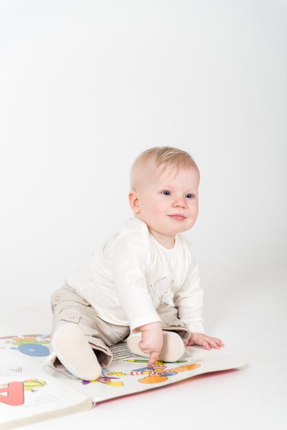 Little baby sits on the book on the white