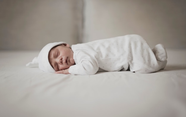 Foto piccolo bambino che dorme su fogli bianchi