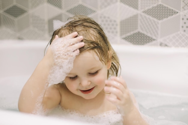 Little baby taking bath closeup face portrait of smiling girl health care and kids hygiene