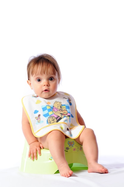 Little baby with bib sitting on potty