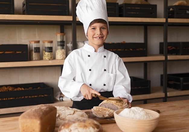 Little baker cutting bread and smiling