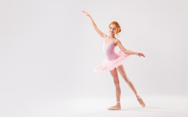 Foto piccola ballerina in uno studente dell'accademia tutu rosa in posa su uno sfondo bianco