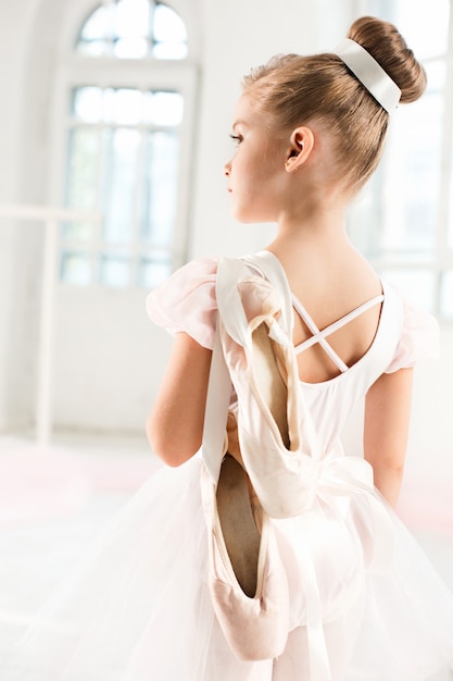 Little ballerina girl in a tutu. Adorable child dancing classical ballet in a white studio.