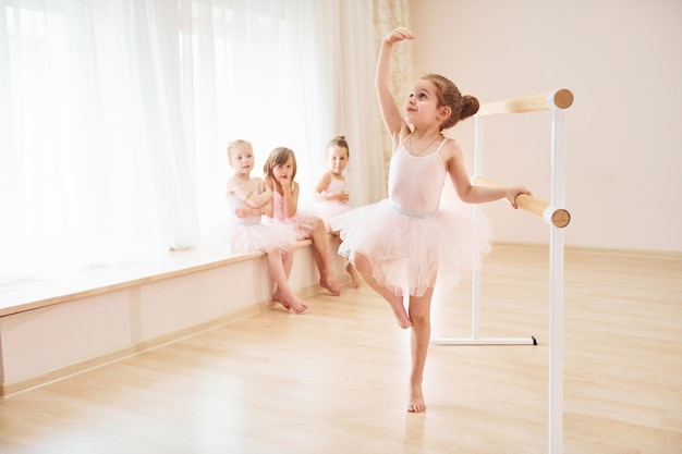 Little ballerinas in pink uniforms preparing for performance